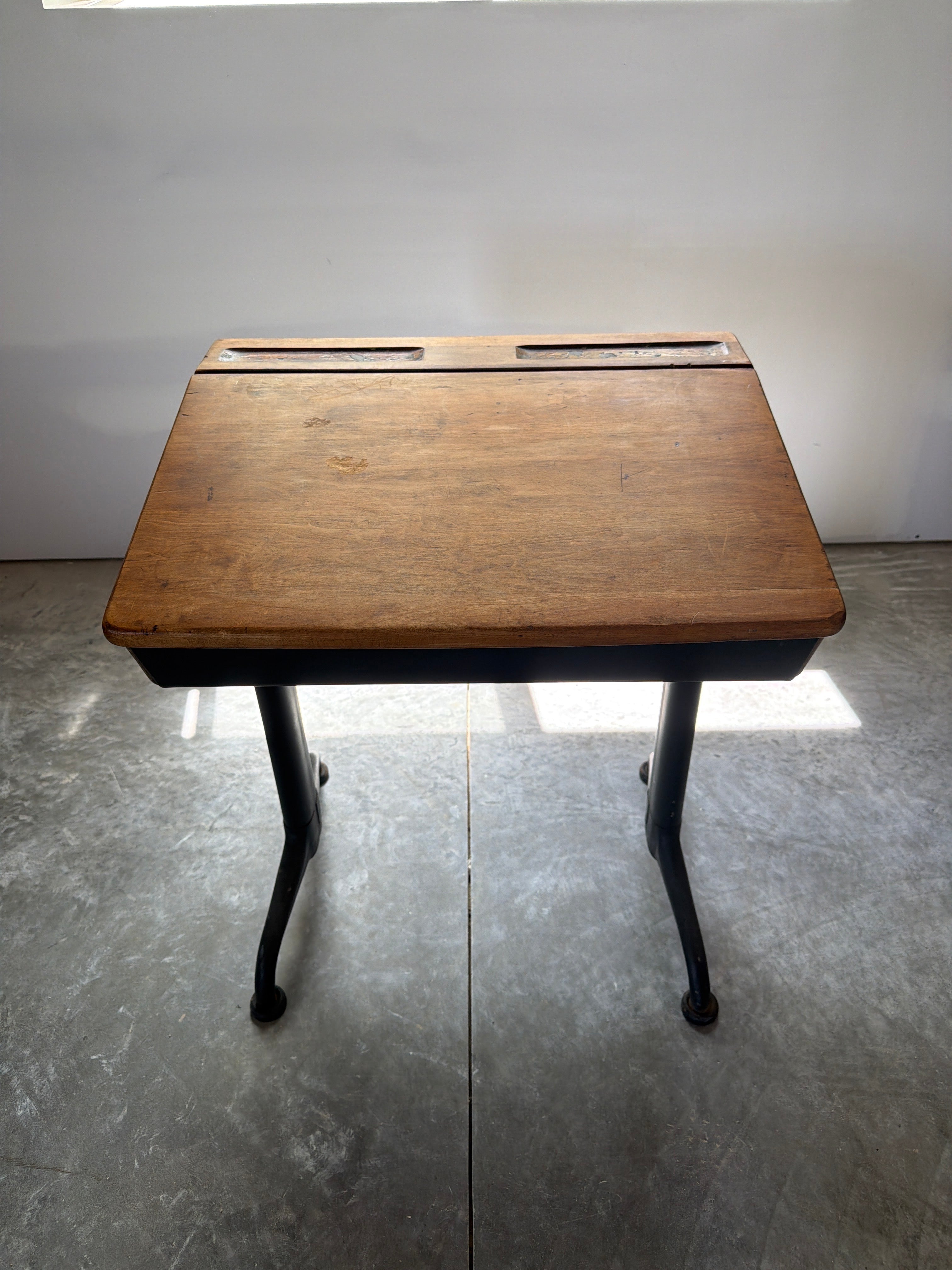 Lift-top schoolhouse desk showing preserved wood surface and aged material character